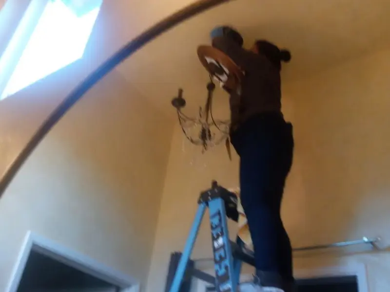 Electrician installing a chandelier in a Carrollton residence